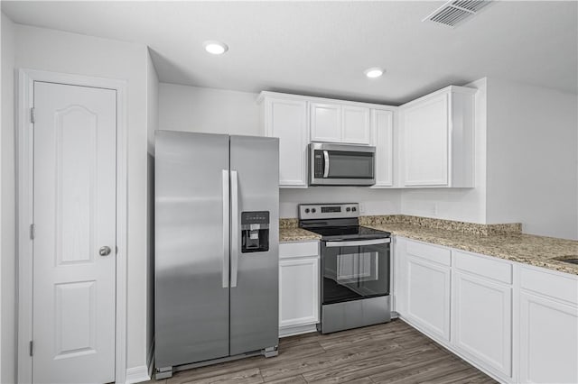 7724 104th Ave, Vero Beach, FL 32967 - kitchen featuring stainless steel appliances, white cabinetry, wood finished floors, light stone counters, and recessed lighting