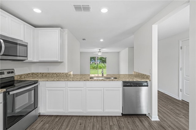 7724 104th Ave, Vero Beach, FL 32967 - kitchen with stainless steel appliances, a sink, white cabinetry, wood finished floors, and light stone countertops