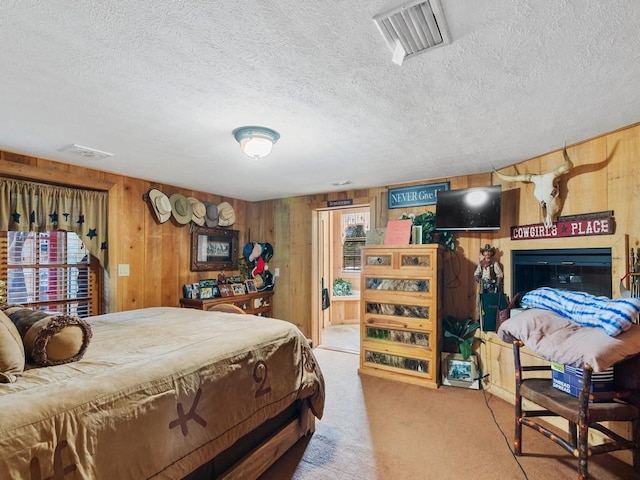 bedroom featuring carpet flooring, a textured ceiling, and wood walls