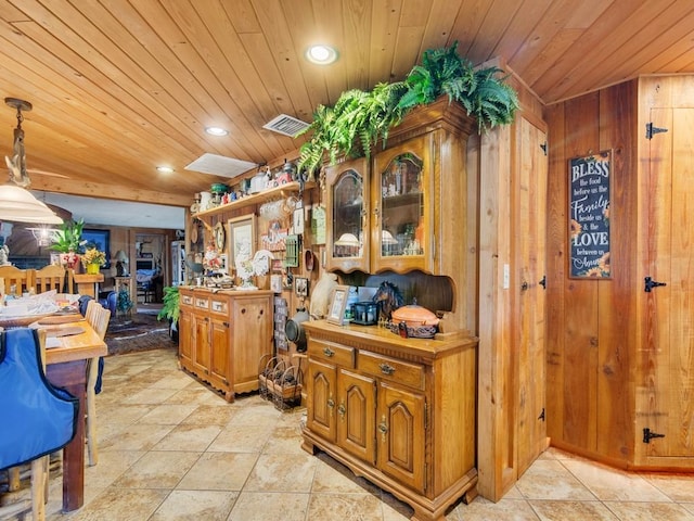 kitchen with hanging light fixtures, wood ceiling, and wood walls