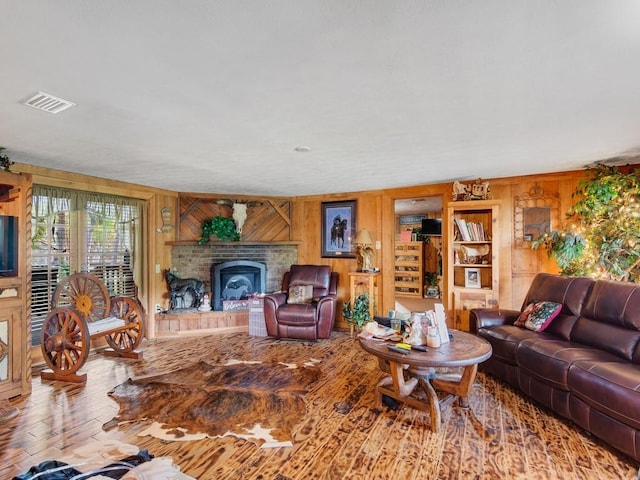 living room featuring hardwood / wood-style flooring, a fireplace, and wood walls