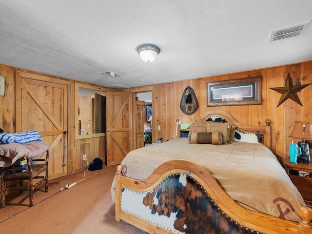 carpeted bedroom featuring a textured ceiling and wooden walls