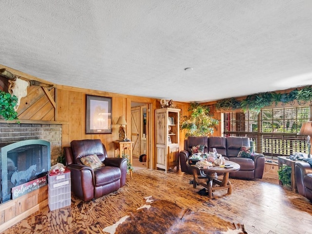 living room featuring wooden walls, a fireplace, hardwood / wood-style floors, and a textured ceiling