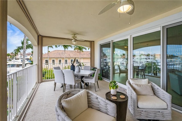 sunroom with ceiling fan and a water view