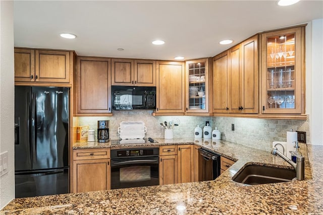 kitchen with light stone counters, sink, decorative backsplash, and black appliances