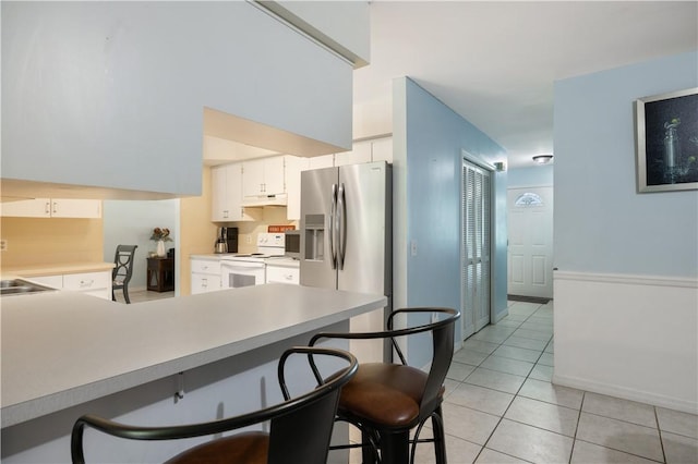 1635 71st Ct, Vero Beach, FL 32966 - kitchen featuring electric range, under cabinet range hood, a breakfast bar area, light tile patterned floors, and light countertops
