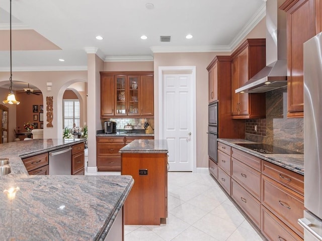 4335 65th Dr, Vero Beach, FL 32967 - kitchen with wall chimney range hood, a center island, stainless steel appliances, brown cabinets, and dark stone counters
