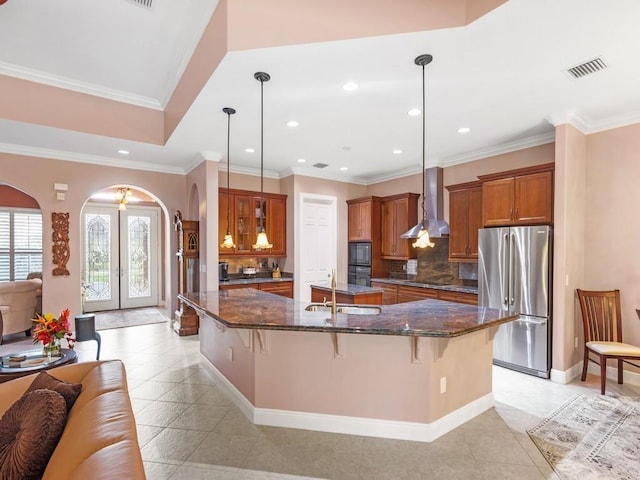 4335 65th Dr, Vero Beach, FL 32967 - kitchen with black appliances, arched walkways, wall chimney exhaust hood, a large island with sink, and a sink