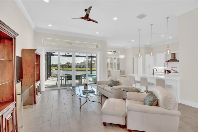 living room with sink, ceiling fan, and a water view