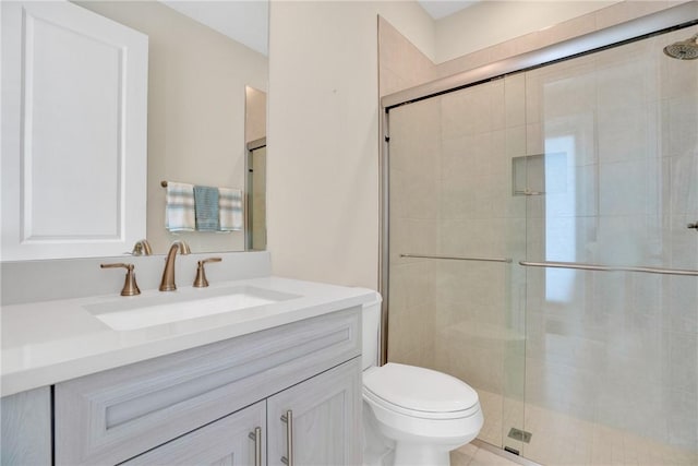 bathroom with toilet, a shower with shower door, and vanity