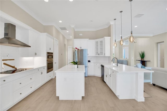 kitchen with a center island, white cabinetry, wall chimney exhaust hood, hanging light fixtures, and appliances with stainless steel finishes