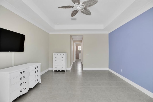 interior space featuring ceiling fan, a raised ceiling, and light tile patterned floors