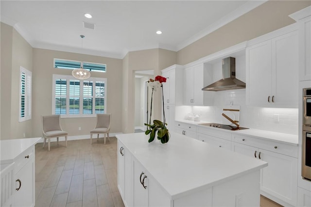 kitchen featuring backsplash, hanging light fixtures, black electric cooktop, a kitchen island, and wall chimney range hood