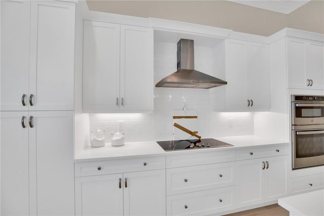 kitchen with white cabinets, wall chimney exhaust hood, tasteful backsplash, stainless steel double oven, and black electric cooktop