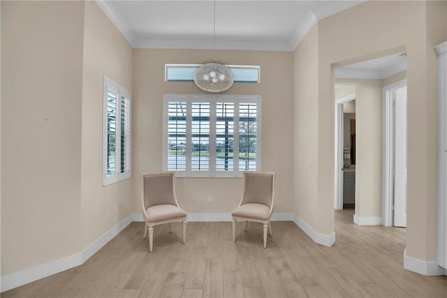 sitting room with ornamental molding, light hardwood / wood-style flooring, and an inviting chandelier