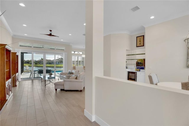 hallway featuring beverage cooler, light hardwood / wood-style flooring, crown molding, and a water view