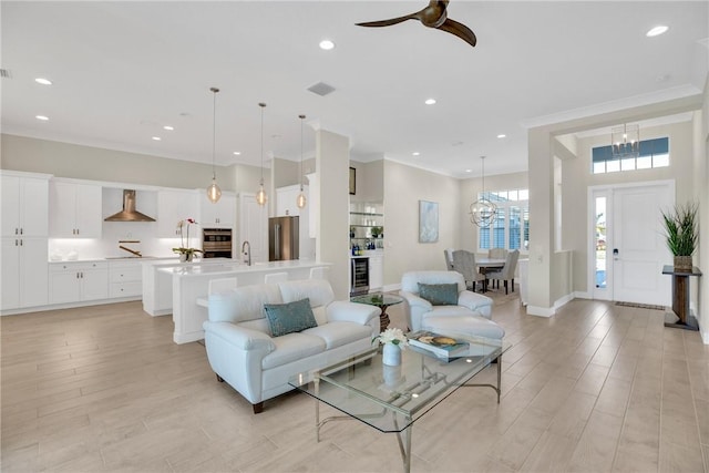 living room featuring ceiling fan, crown molding, light hardwood / wood-style floors, and sink