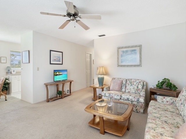 living room featuring a textured ceiling, light colored carpet, and ceiling fan