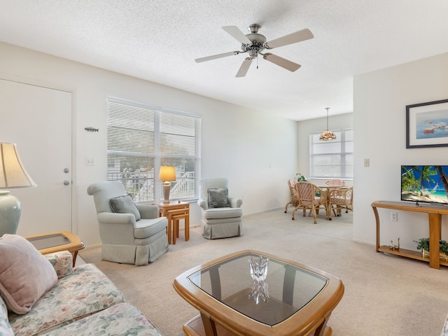 living room with ceiling fan, a textured ceiling, and light carpet