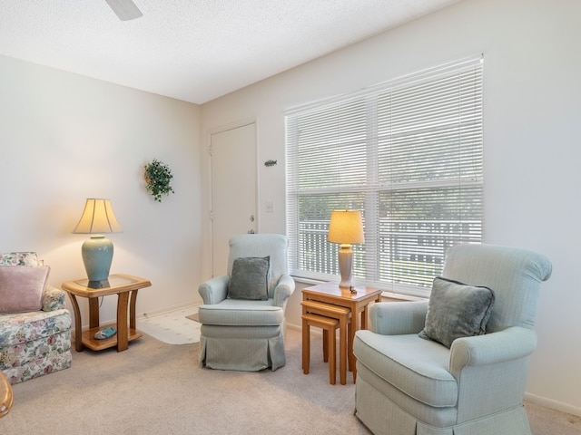 sitting room with a textured ceiling, carpet flooring, and ceiling fan