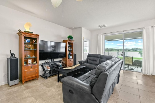 living room featuring baseboards, light tile patterned flooring, visible vents, and a ceiling fan