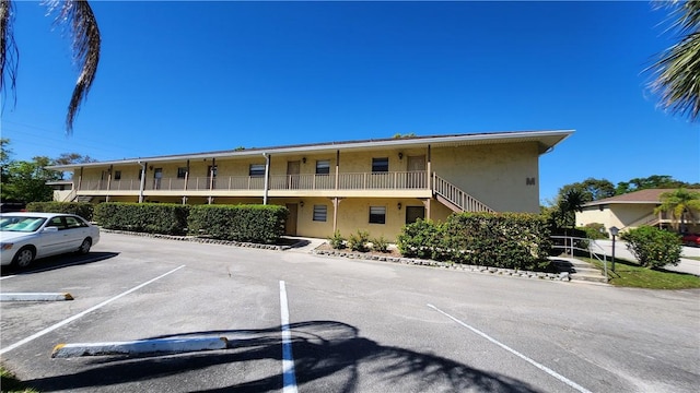 view of property with uncovered parking and stairway