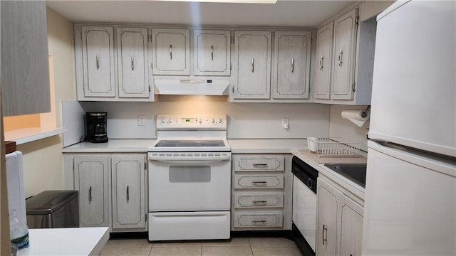 kitchen featuring white appliances, light tile patterned floors, light countertops, under cabinet range hood, and a sink