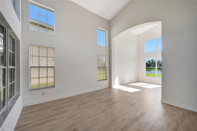 spare room with a high ceiling and light hardwood / wood-style flooring