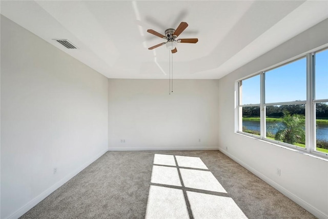 spare room with a water view, ceiling fan, and light colored carpet