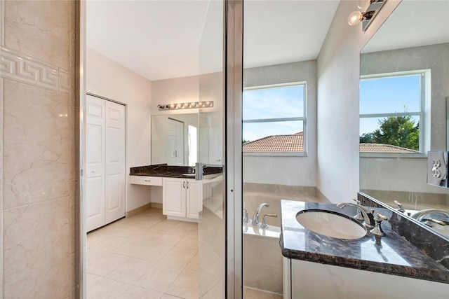 bathroom with tile patterned floors, a tub, a wealth of natural light, and vanity