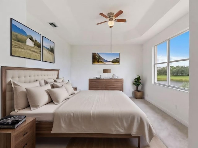 bedroom featuring carpet, ceiling fan, and a water view