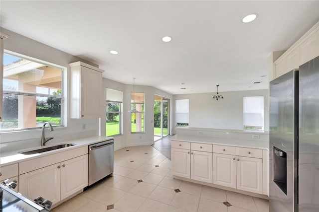 kitchen featuring white cabinets, decorative light fixtures, stainless steel appliances, and sink