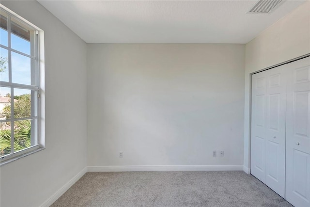 unfurnished bedroom featuring light colored carpet and a closet