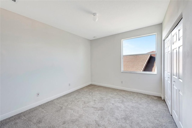 unfurnished bedroom with light colored carpet and a closet