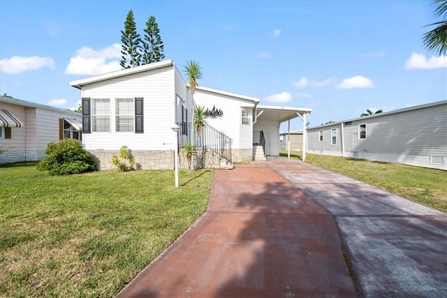 641 Hyacinth Cir, Barefoot Bay, FL 32976 - manufactured / mobile home with a carport, a front lawn, and concrete driveway