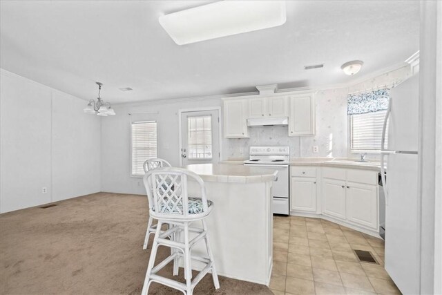 641 Hyacinth Cir, Barefoot Bay, FL 32976 - kitchen featuring white cabinets, a kitchen breakfast bar, light countertops, white appliances, and a center island