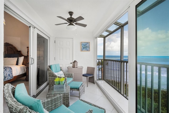 sunroom / solarium featuring a water view, ceiling fan, and a beach view