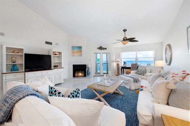 living room with a tile fireplace, vaulted ceiling, ceiling fan, light tile patterned floors, and built in features