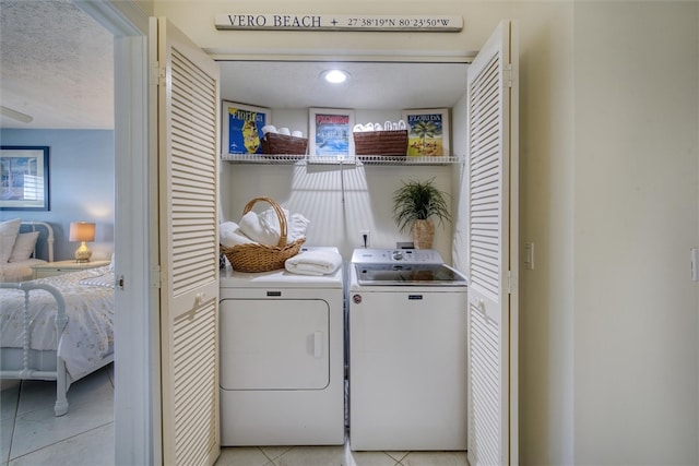 clothes washing area featuring washer and dryer, light tile patterned floors, and a textured ceiling