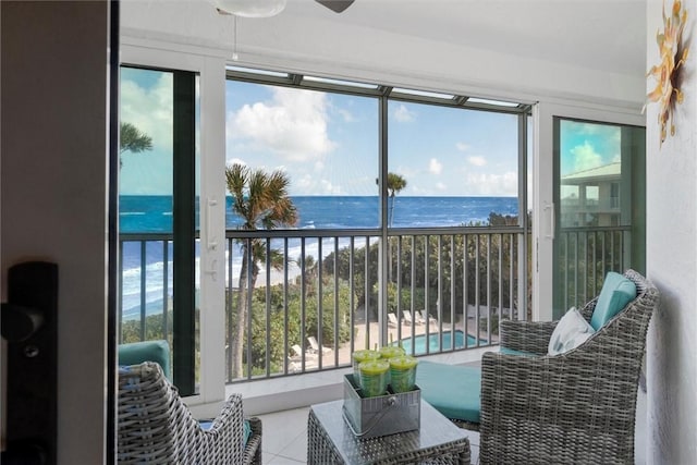 sunroom / solarium with ceiling fan and a water view