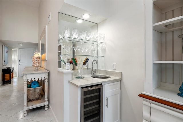 bar featuring wine cooler, light tile patterned floors, sink, and white cabinets