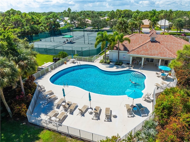 view of swimming pool featuring tennis court and a patio area