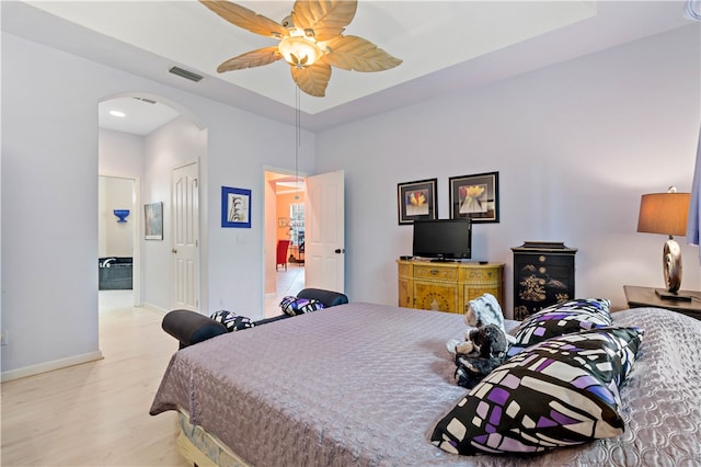 bedroom with ensuite bathroom, ceiling fan, a closet, and light wood-type flooring