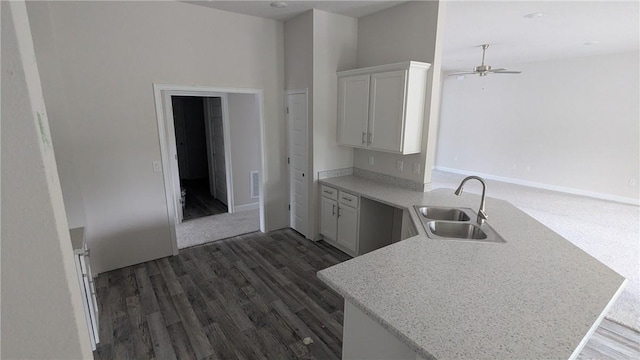 kitchen with a sink, a peninsula, ceiling fan, dark wood-type flooring, and white cabinets