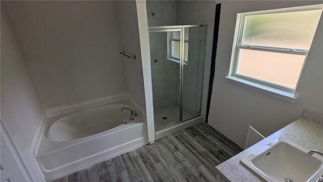 bathroom featuring a sink, a stall shower, wood finished floors, and a bath