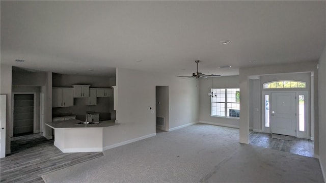 kitchen featuring a sink, white cabinetry, baseboards, and ceiling fan