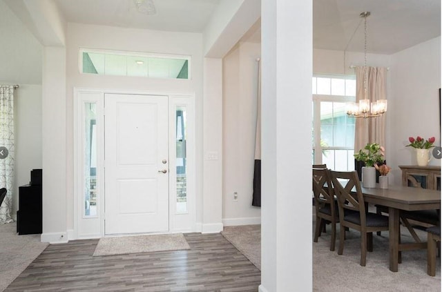 foyer entrance with a chandelier, baseboards, and wood finished floors