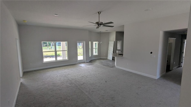 unfurnished living room with light colored carpet, baseboards, and ceiling fan