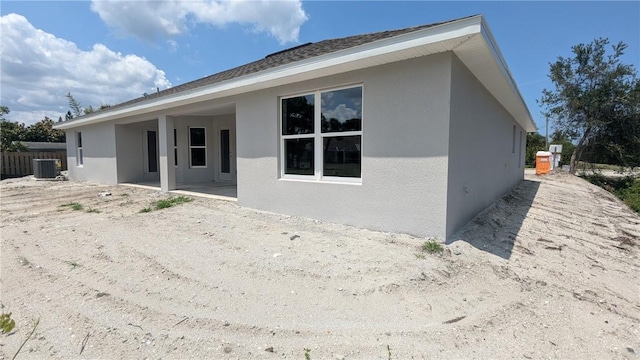 back of house featuring stucco siding and central air condition unit