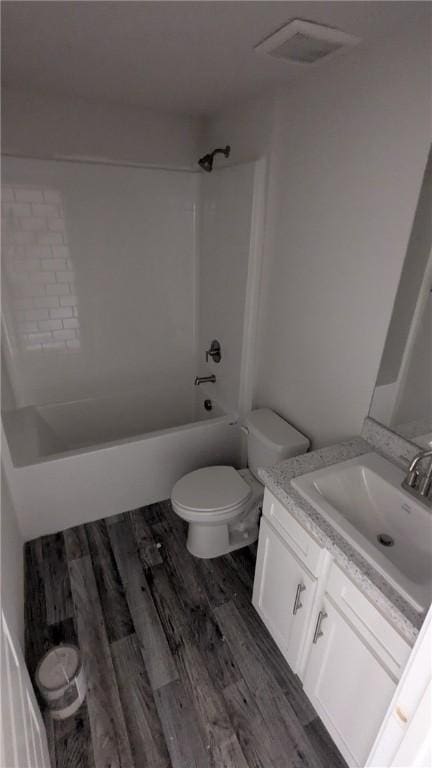 bathroom featuring toilet, vanity, washtub / shower combination, and wood finished floors
